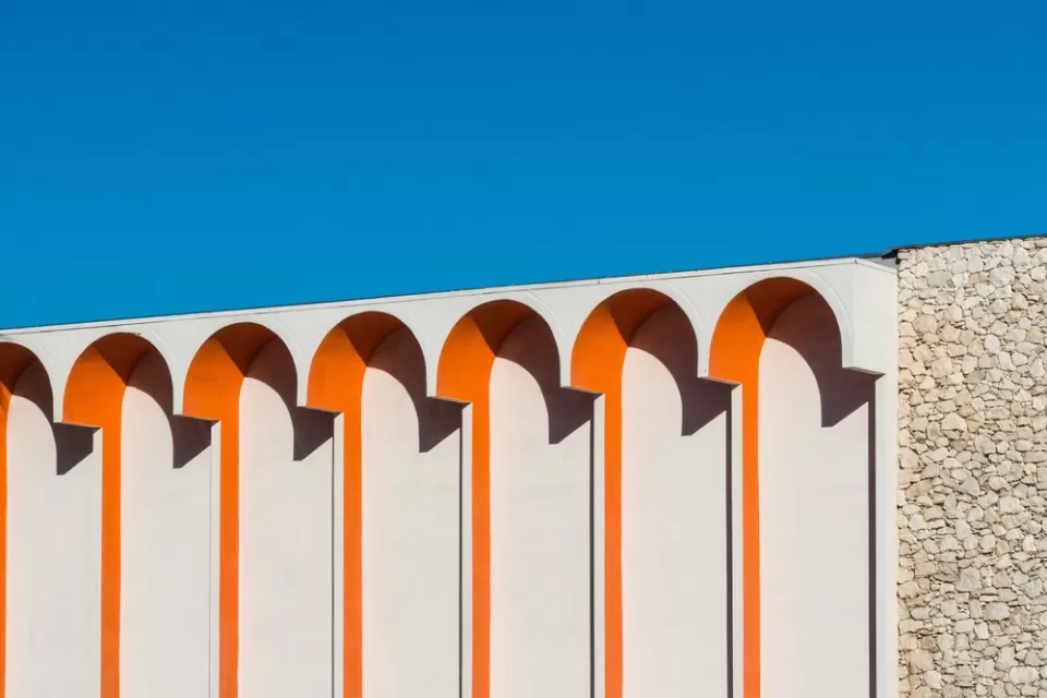 Close-up of white building with orange arch details against blue sky in Palm Springs, California